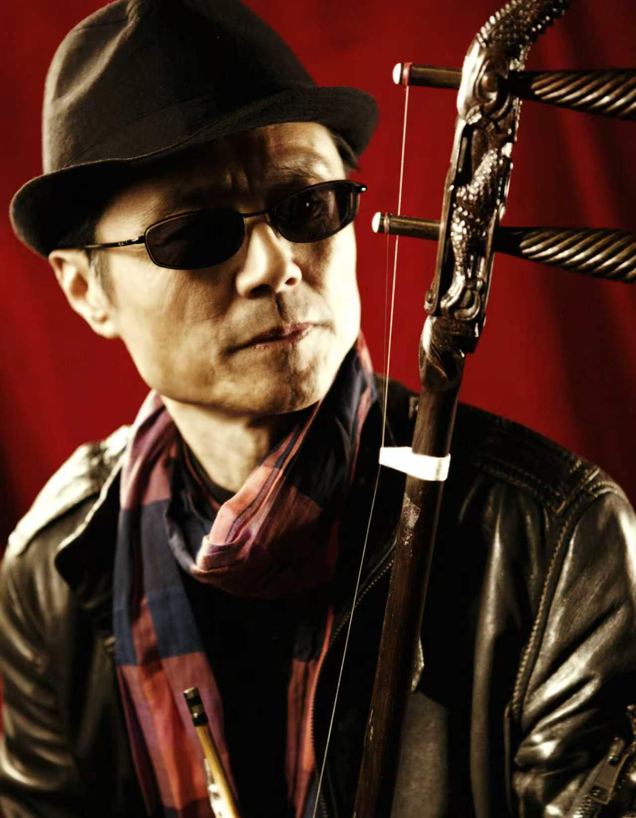 Hong Wang portrait with erhu against a red background