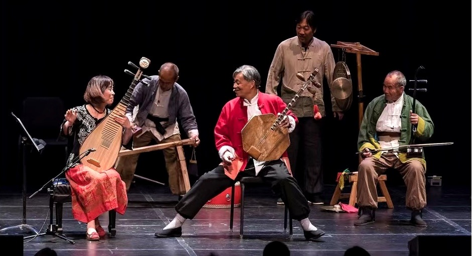 Wu Man performing on stage with traditional musicians