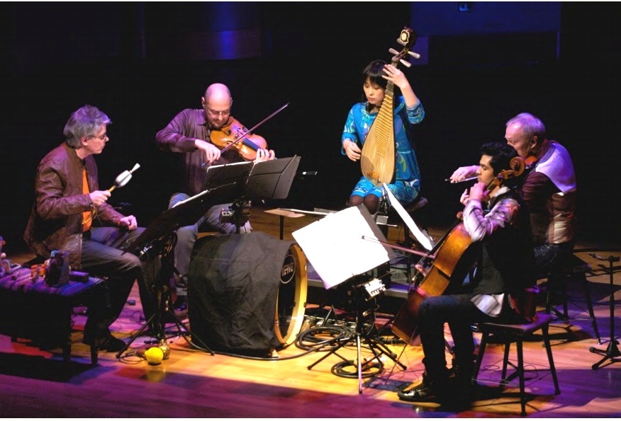 Wu Man performing on stage with an ensemble